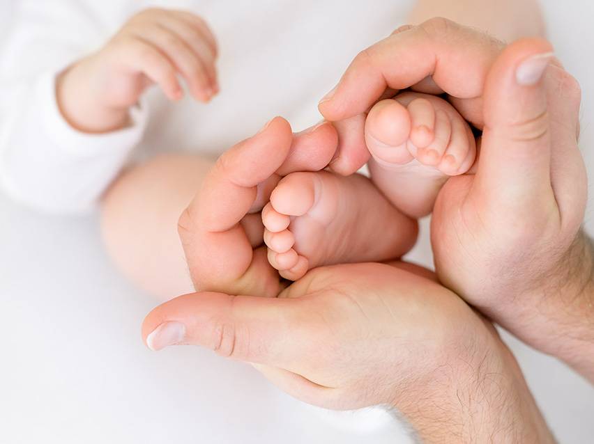 Babys Füße liebevoll in Händen gehalten.