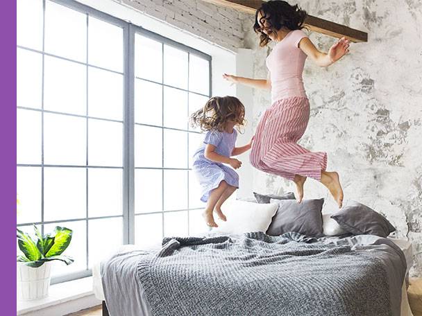 Mutter und Tochter springen auf dem Bett.