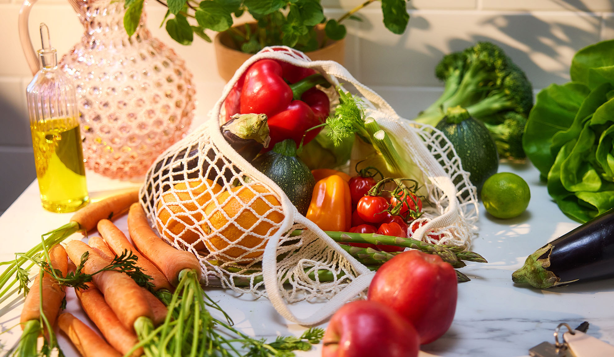 Frisches Gemüse und Obst, darunter Paprika, Orangen und Karotten, in einer Einkaufstasche.