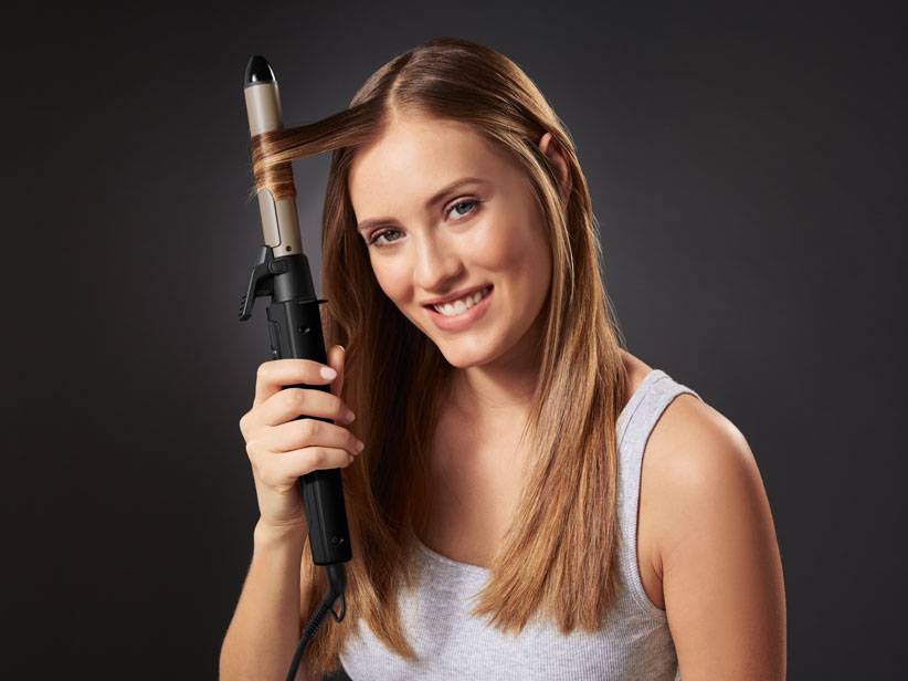 Frau benutzt einen Lockenstab.