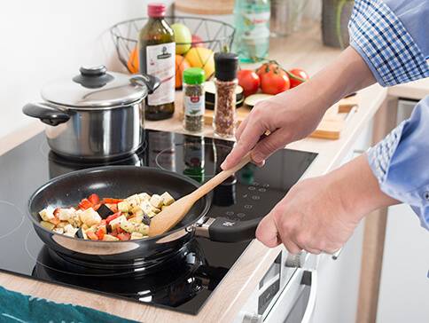 Essen wird in einer Pfanne und einem Topf auf dem Herd zubereitet.