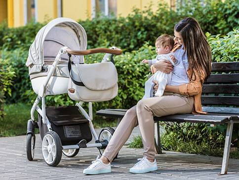 Kinderwagen mit Baby und Mutter im Park.