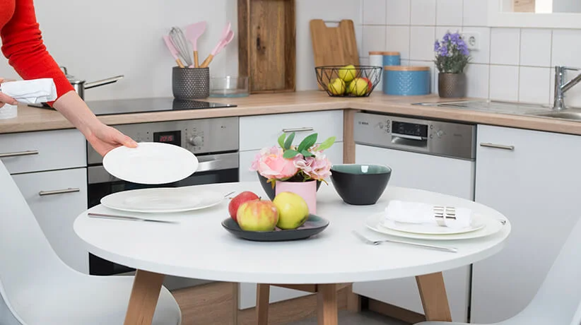 Weißer Tisch, Geschirr und Obst in der Küche.