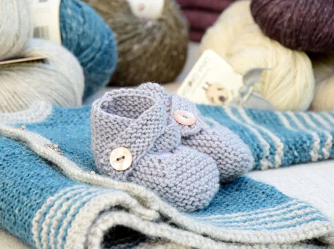 Gestrickte Babyschuhe und Garn.