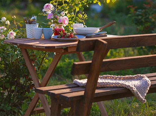 Garten-Tisch, Bank, Tassen und Erdbeeren.