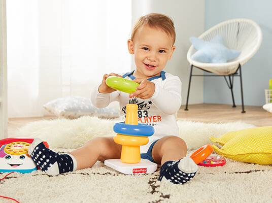 Baby spielt mit Fisher-Price Spielzeug: Stapelturm und Telefon.
