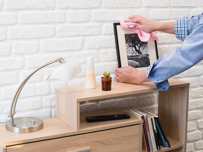 Reinigung von Kommode, Schreibtischlampe und Bilderrahmen.