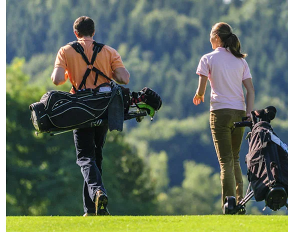 Golfer mit Taschen und Schlägern auf einem Golfplatz im Grünen.