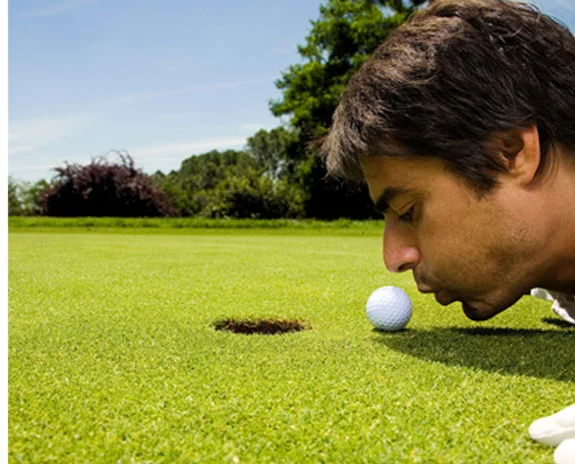 Golfer inspiziert den Ball vor dem Putt auf dem Grün.