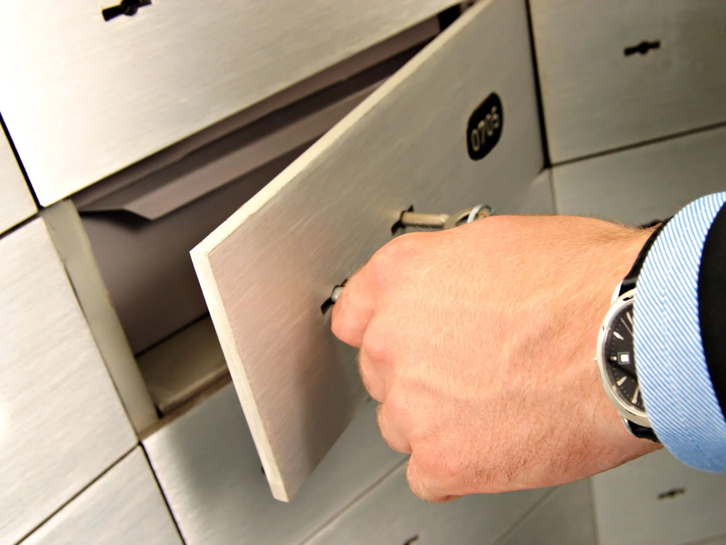 Hand öffnet metallene Schließfächer mit einem Schlüssel.