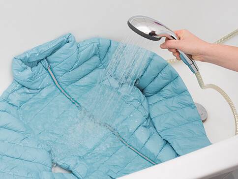 Daunenjacke wird unter der Dusche gewaschen.