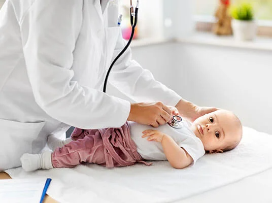 Ärztin untersucht Baby mit Stethoskop.