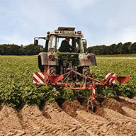 Traktor bearbeitet Feld mit Anbaugerät.