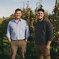 Zwei Männer stehen in einem Apfelgarten.