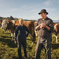 Bauer und Bäuerin mit ihren Rindern auf der Weide.