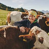 Bauernfrau streichelt ihre Kühe auf der Weide.