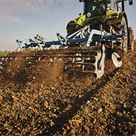 Ein Traktor bearbeitet mit einer Kreiselegge den Ackerboden.