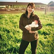 Frau hält ein weißes Huhn auf einer Farm.