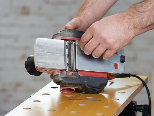 Holzbearbeitung: Elektrische Hobelmaschine und Werkbank.