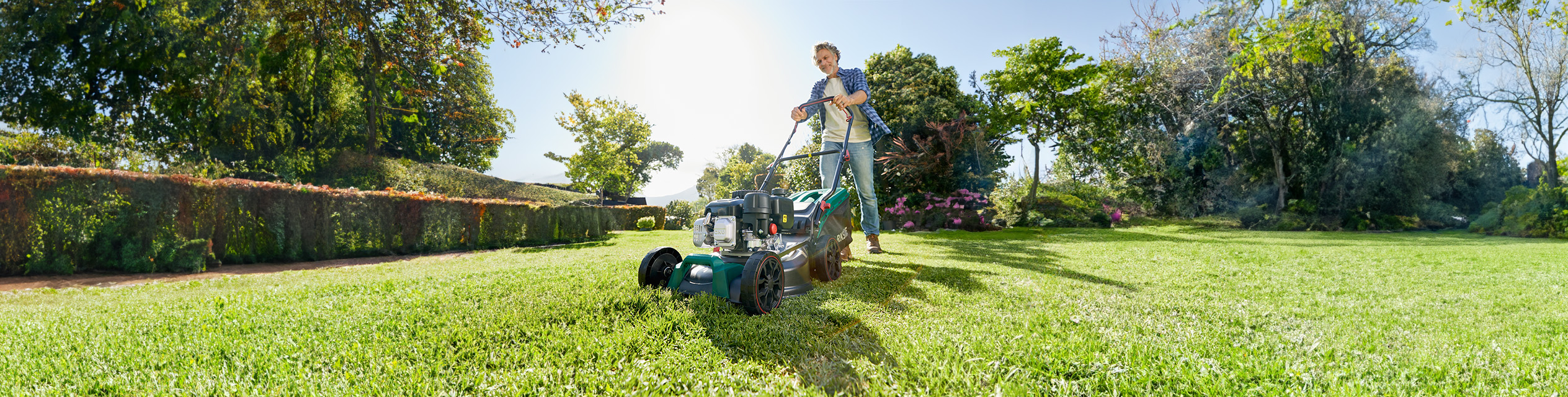 Mann benutzt einen Benzinrasenmäher im Garten.