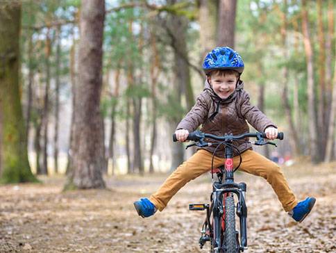 Ein lächelndes Kind fährt mit dem Fahrrad im Wald.