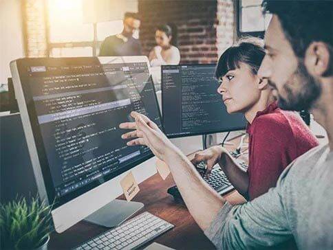 Zwei Programmiererinnen arbeiten an Computern.