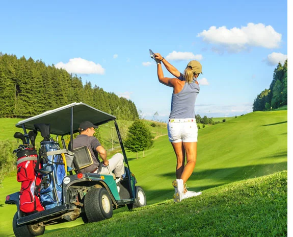 Golfwagen und Golferin auf dem Platz.