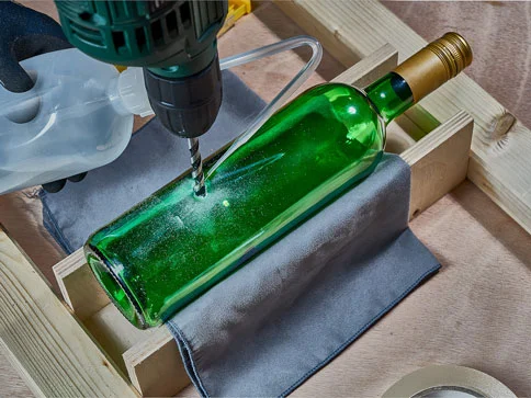 Weinflasche, Bohrmaschine und Holzgestell.