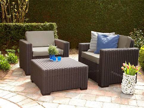 Rattan-Sitzgruppe: zwei Sessel und Tisch.