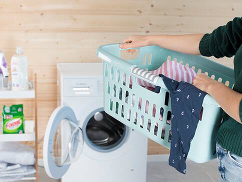 Wäschekorb mit Wäsche und Waschmaschine.