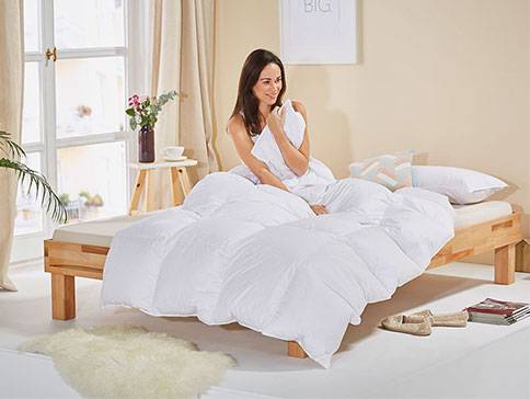 Daunenbett und Holzbett.