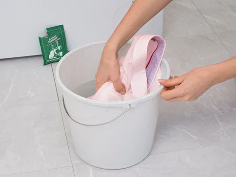 Helles Hemd in einem Eimer mit Waschmittel eingeweicht.