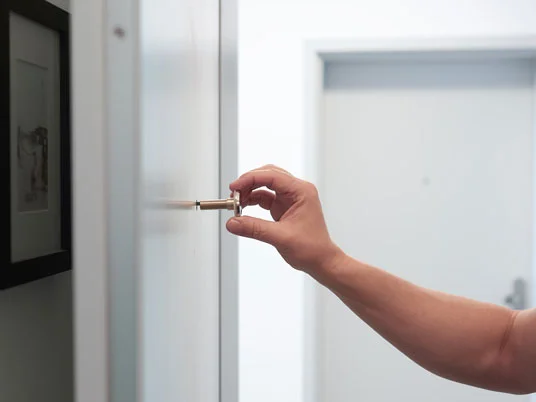 Hand öffnet Türschloss.