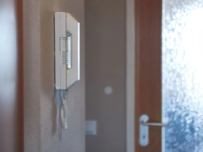 An der Wand montierter Türsprecher und Tür.