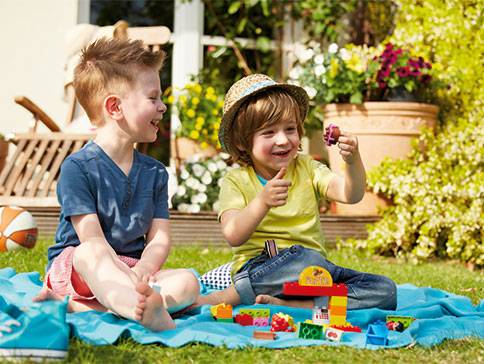 Kinder spielen draußen mit Lego Steinen.