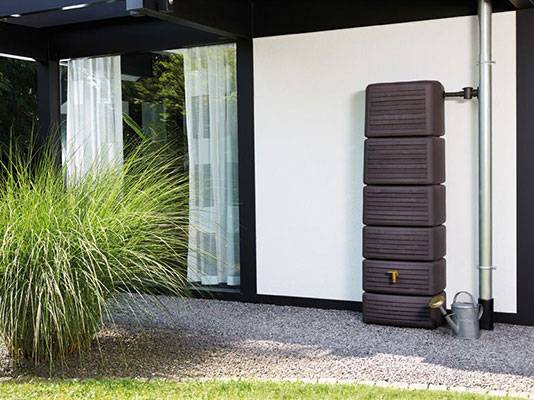 Brauner Regenspeicher an Hauswand.