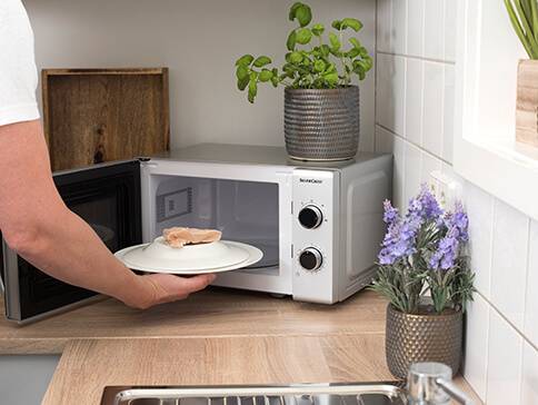 Mikrowelle, Teller und Fleisch.