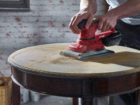 Einhell Schleifmaschine schleift einen Tisch.