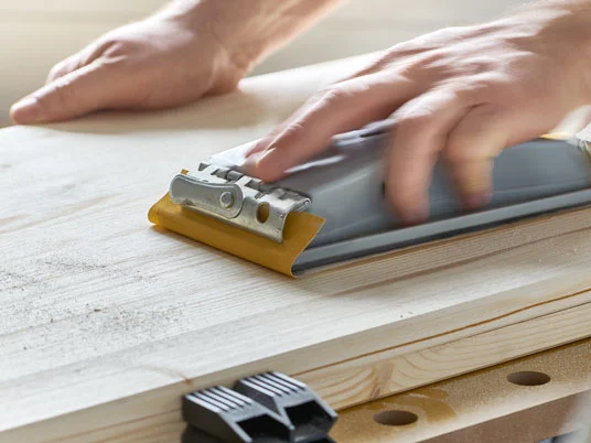 Holz wird mit einer Schleifmaschine bearbeitet.