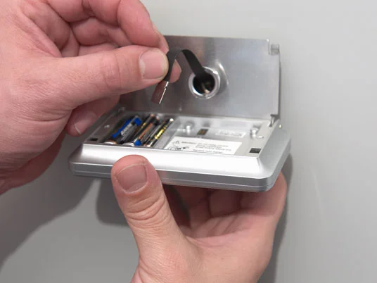 Person wechselt Batterien in einem Detektor.