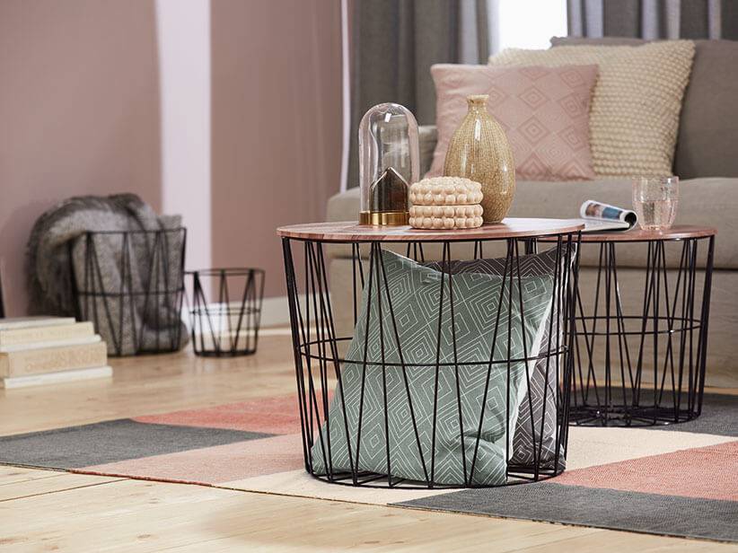 Schwarz-weiße Beistelltische mit Metallgestell und Aufbewahrungskörbe im Wohnzimmer.