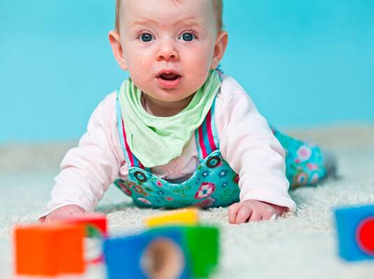 Baby spielt mit bunten Holzwürfeln.