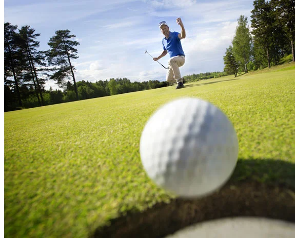 Golfer schlägt Ball auf dem Grün.