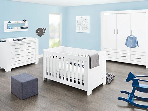 Weißes Babybett, Kommode und Kleiderschrank im Kinderzimmer.