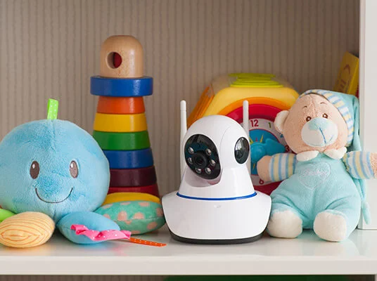 Überwachungskamera, Plüschtiere und Holzspielzeug im Regal.