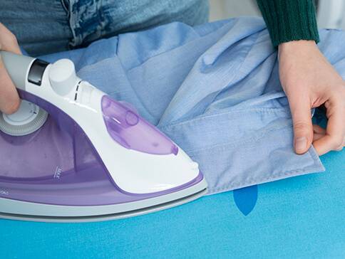 Bügeleisen und blaues Hemd.