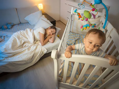 Mutter schläft, Baby im Bettchen.