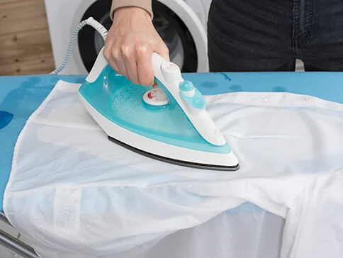 Ein Bügeleisen bügelt ein Hemd auf einem Bügelbrett.