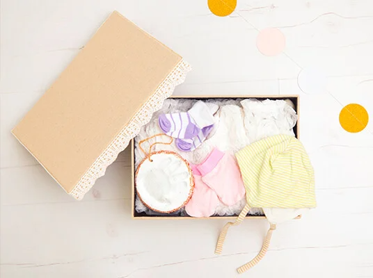 Geschenkbox mit Babykleidung, Socken und Handabdruck.