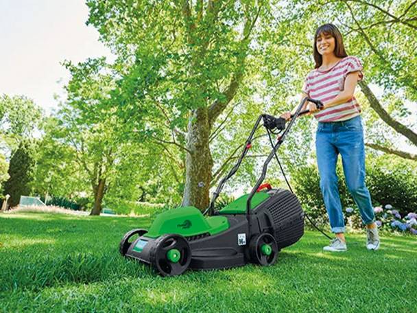 Frau benutzt einen grünen Rasenmäher.